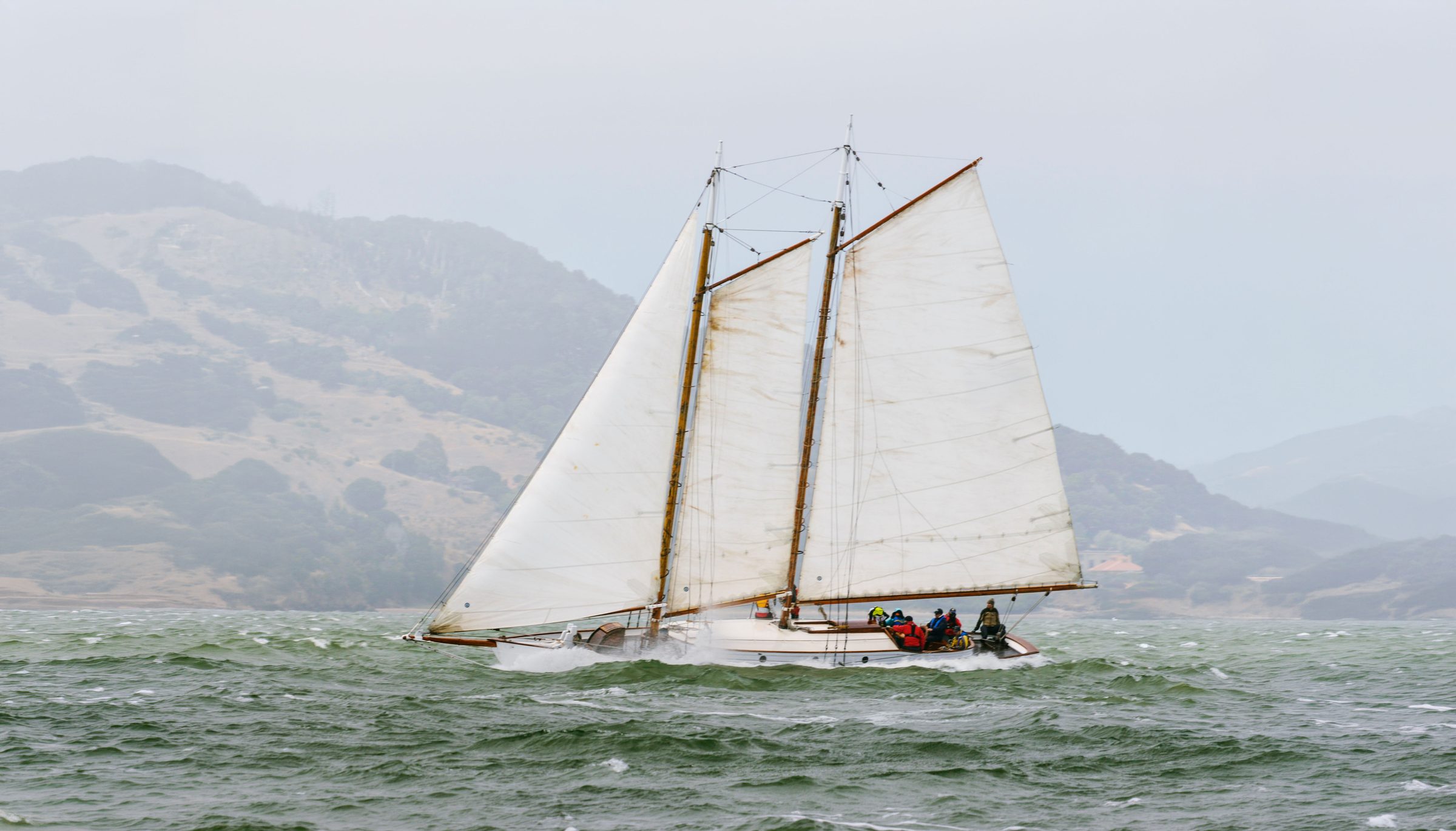 The schooner Yankee under full sail on San Francisco Bay, the Marin hills behind
